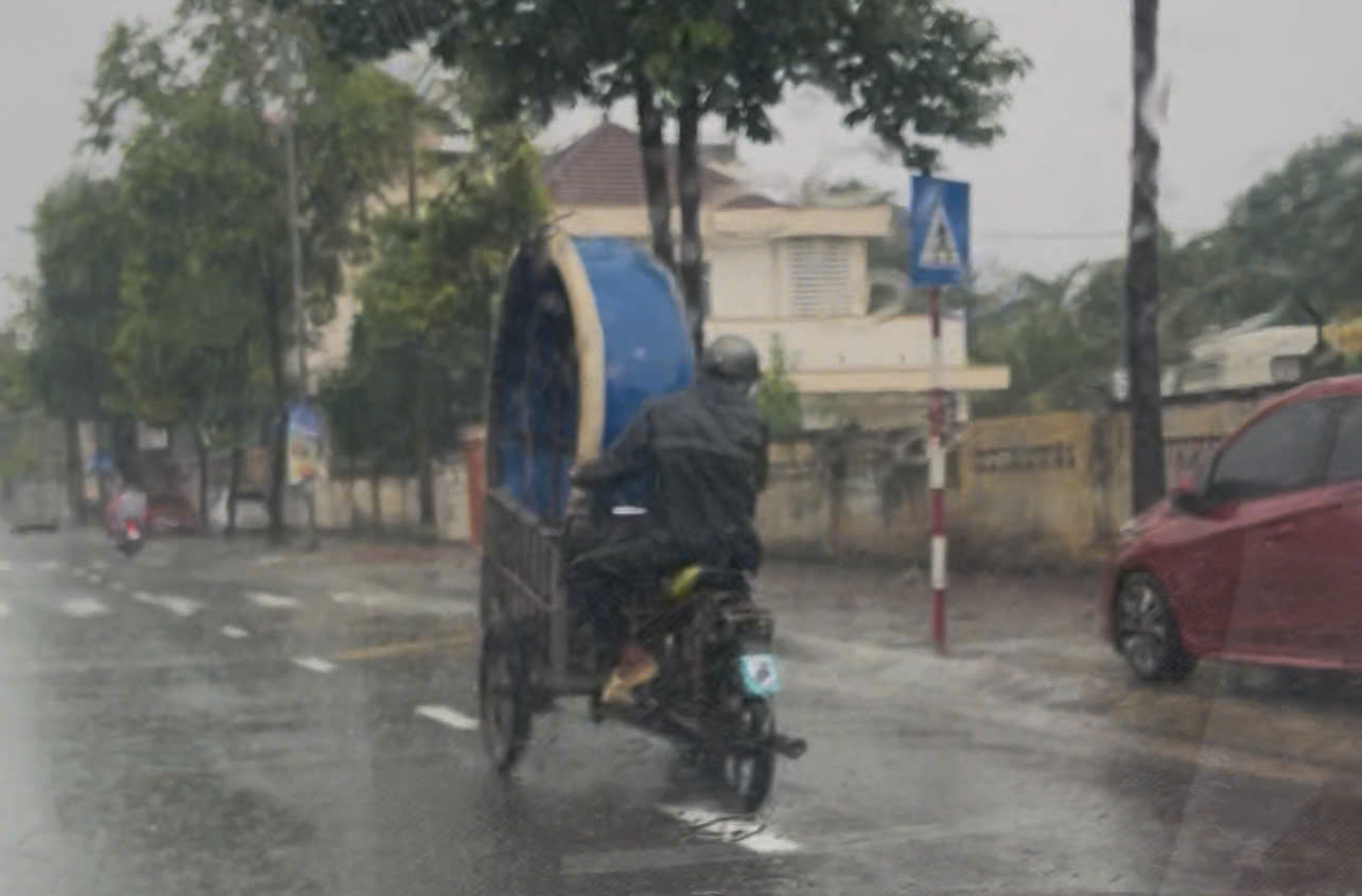 một người dân cố gắng mang thuyền thúng đi cứu người gặp lũ